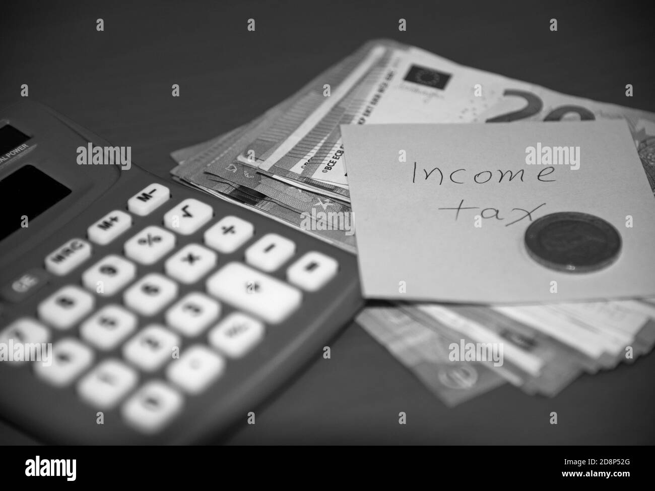 Imposta sul reddito scritta su nota post-it con banconote, moneta e calcolatrice. Concetto: Pagamento dell'imposta sul reddito. Foto Stock