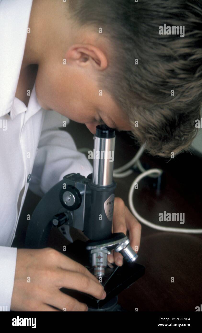 ragazzo della scuola secondaria guardando al microscopio Foto Stock