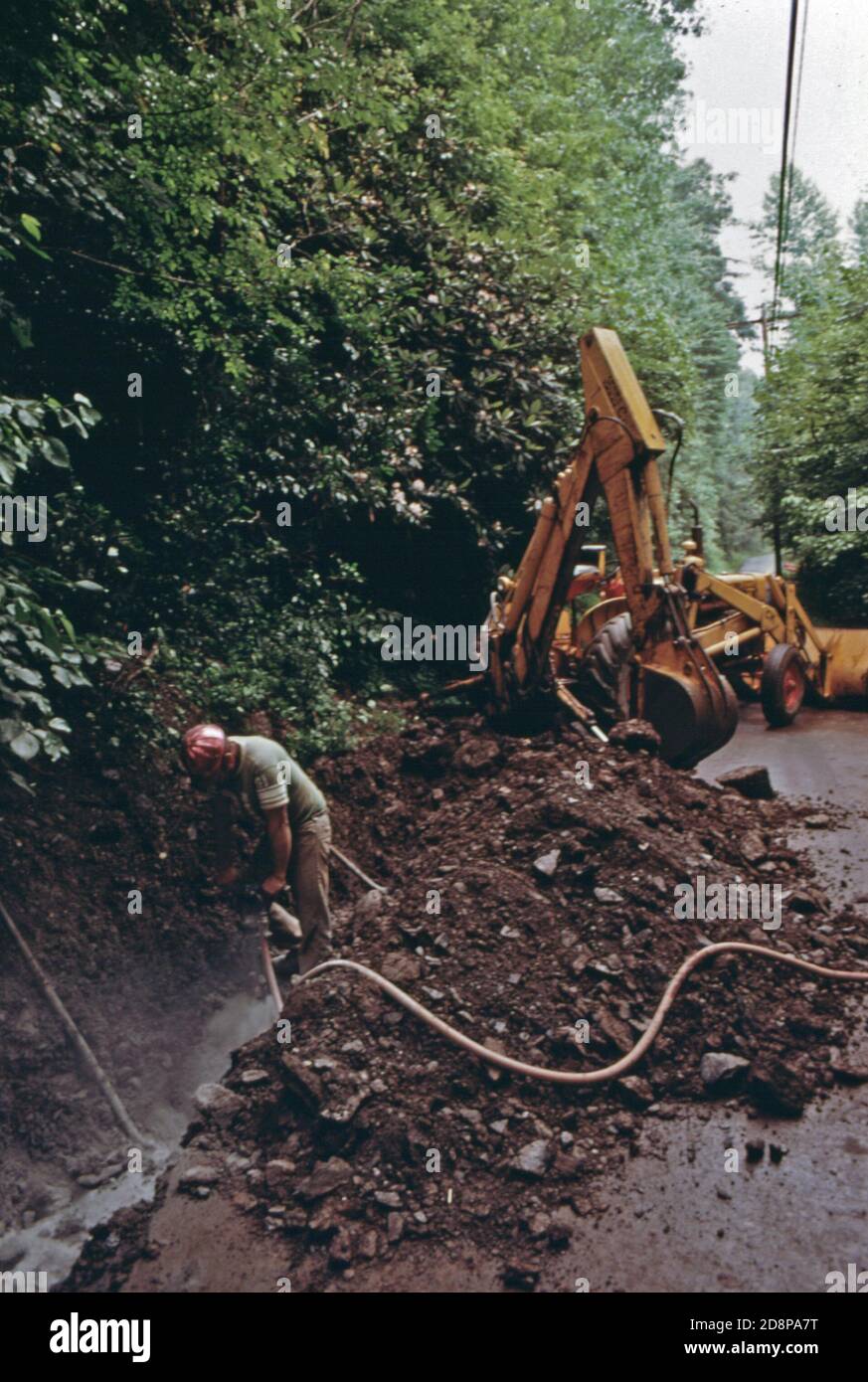 Un lavoratore di costruzione perfora attraverso la roccia solida lungo Escowee Street sulla riva del fiume Chattahoochee prima di posare il tubo per il primo sistema di trattamento delle acque reflue di Helen. Il progetto è diventato una necessità di prendersi cura dei turisti che visitano la piccola comunità montana di circa 270 persone. Nel 1969 funzionari locali; uomini d'affari e residenti hanno approvato la ristrutturazione del quartiere degli affari con un tema alpino bavarese. Il suo successo ha attratto nuove imprese e turisti. Foto Stock