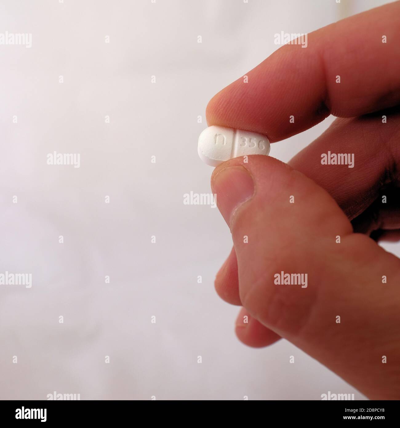 Uomo che tiene un unico idrocodone con la pillola di Acetaminophen prescritta per il dolore e il recupero post-chirurgico; crisi oppioidi e dipendenza. Foto Stock