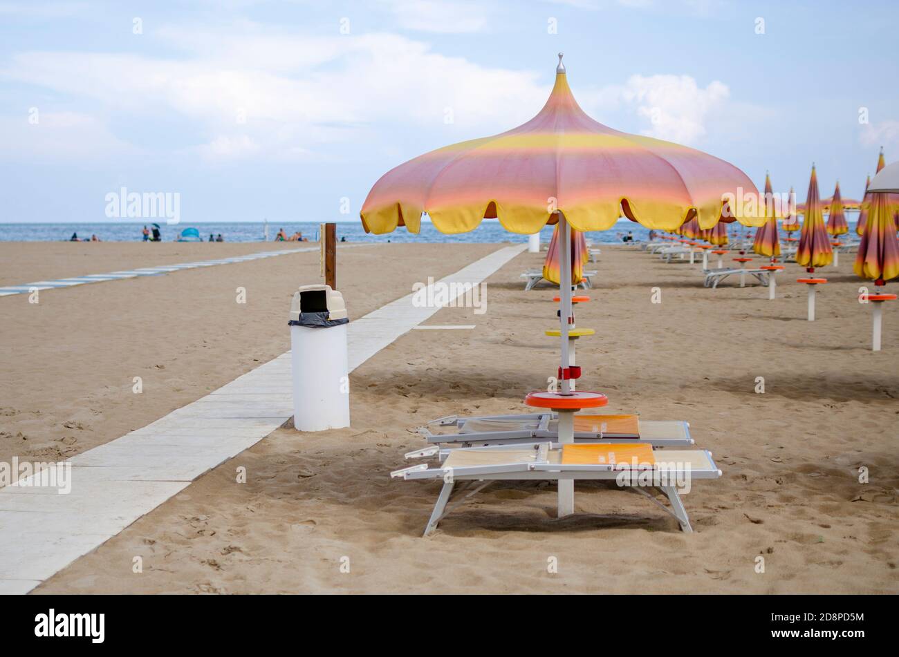 Spiaggia italiana con sabbia e ombrelloni e persone nel distanza Foto stock  - Alamy