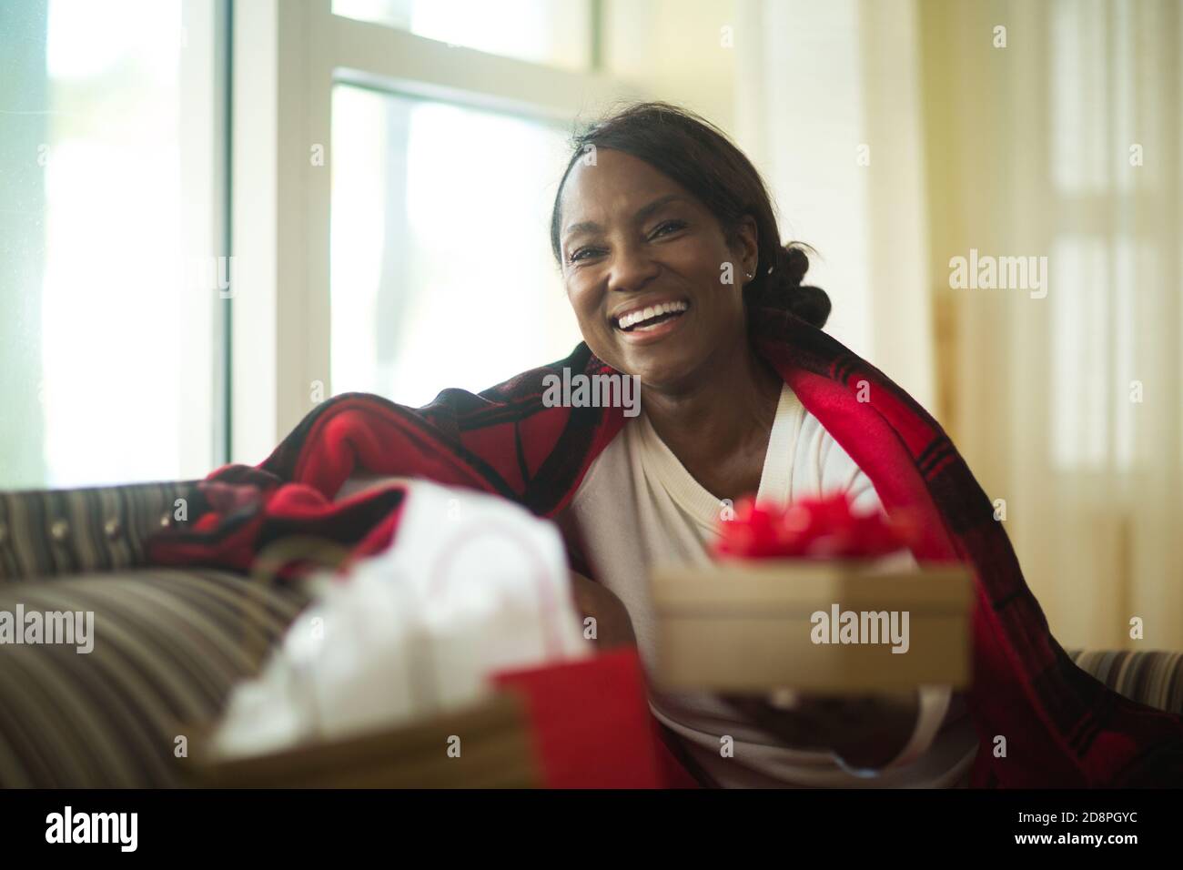 Donna matura seduta sul divano a casa. Foto Stock