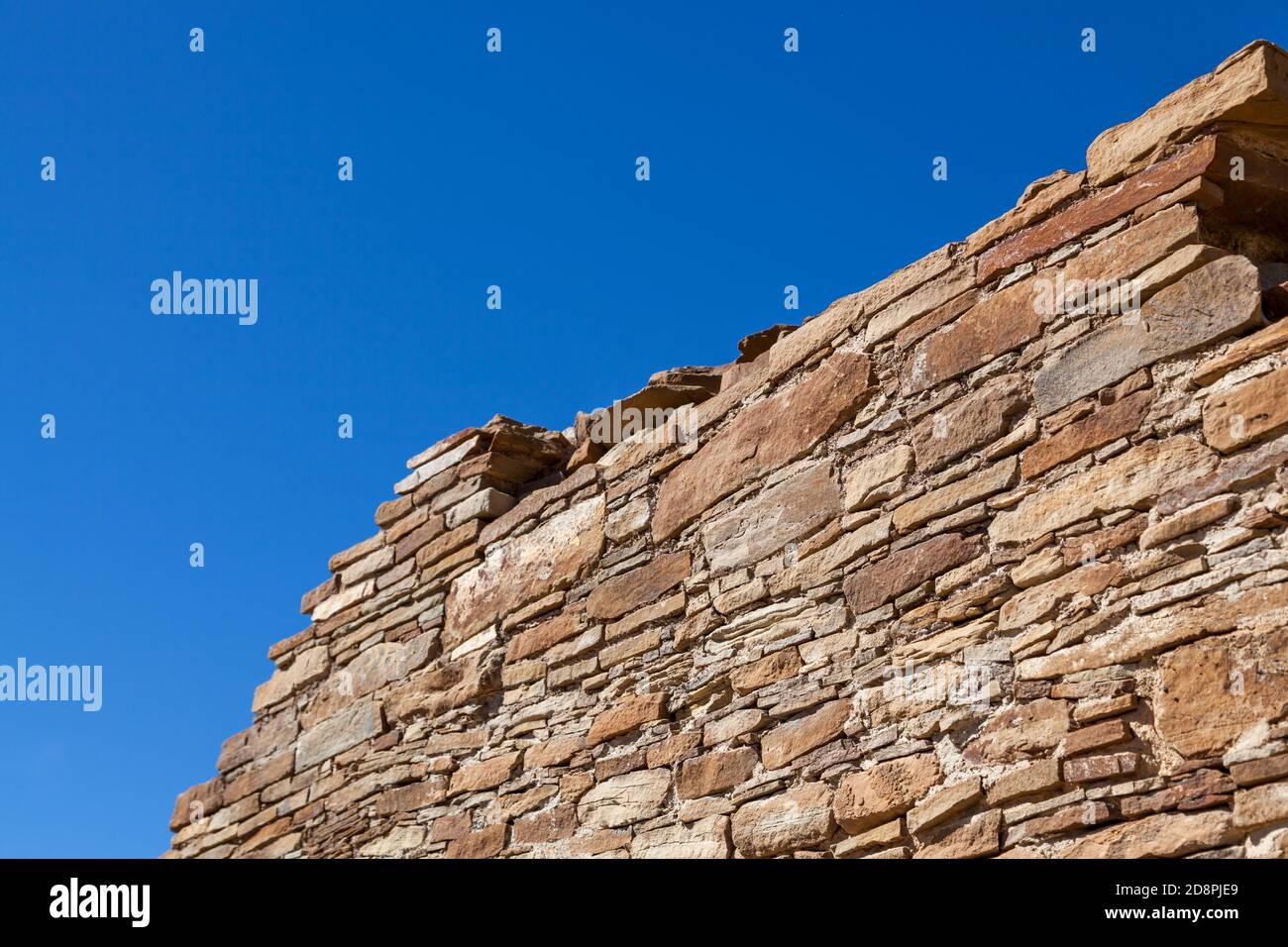 La parte superiore di un'antica parete rocciosa che mostra la superiore maestria del popolo Anasazi contro un cielo blu chiaro. Foto Stock
