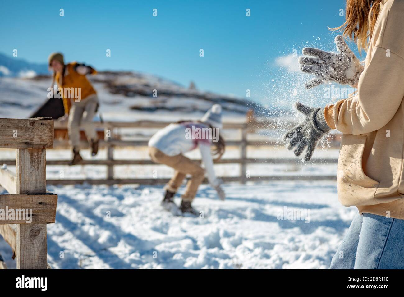 Tre ragazze giocano palle di neve in montagna. Ragazza scuotendo la neve dalle mani Foto Stock