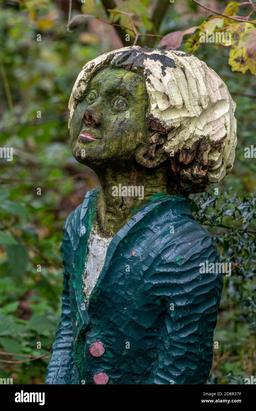 un ornamento giardino o pezzo di statuario giardino in forma di una piccola o giovane ragazza scolpita dal legno nel parco di campagna holt a norfolk. Foto Stock