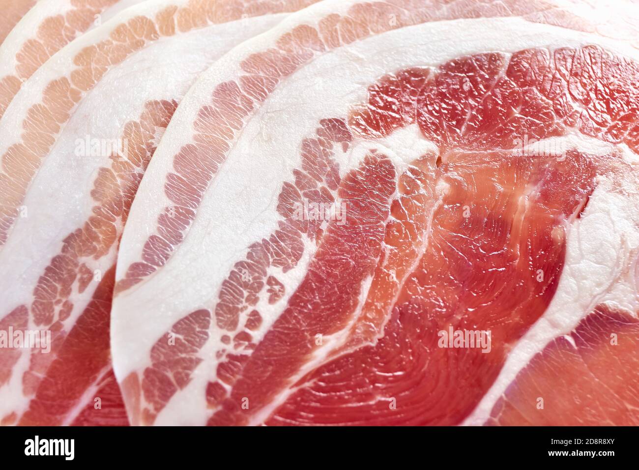Primo piano di pancetta rotonda cruda tagliata a fette. Fondo di carne. Foto Stock