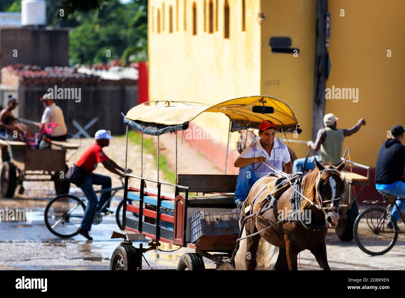 Uomo sorridente che guida un carrello durante l'ora di punta del mattino su una via Trinidad. Cuba Street scene. Foto Stock