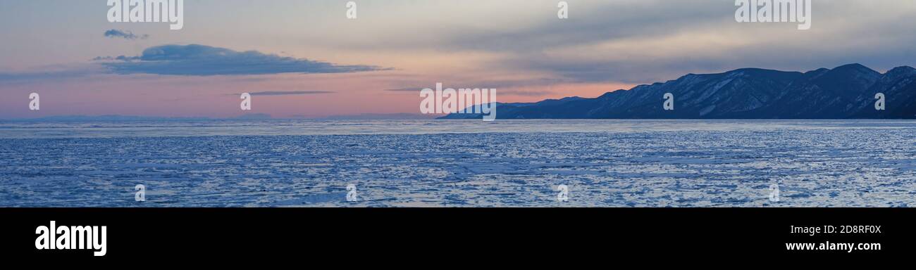 Panorama della superficie ghiacciata del lago Baikal in rosa toni del tramonto Foto Stock