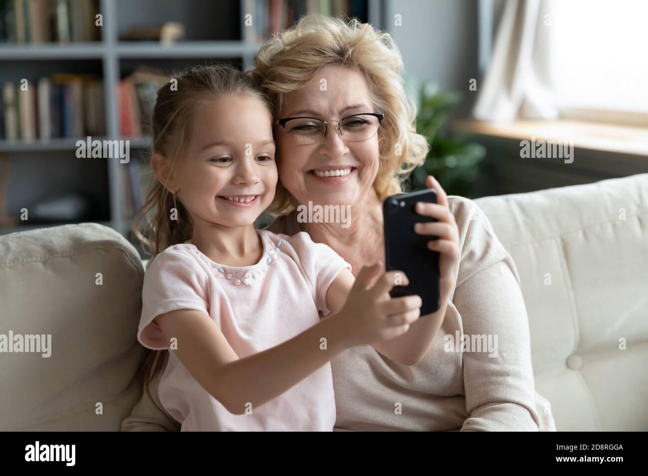 Little cute capretto ragazza registrazione divertente video mobile con Granny. Foto Stock
