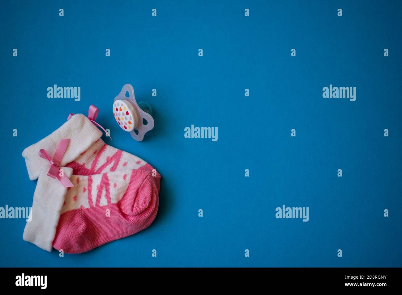 Calze rosa per bambini e succhietto su sfondo blu Foto Stock