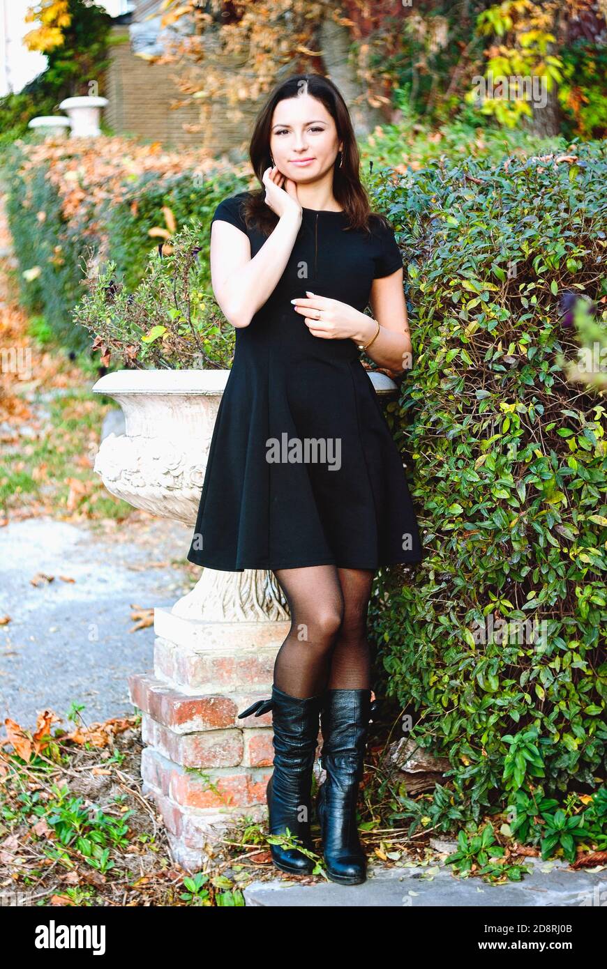 Ritratto di giovane donna felice in un vestito nero che cammina in città d'autunno Foto Stock