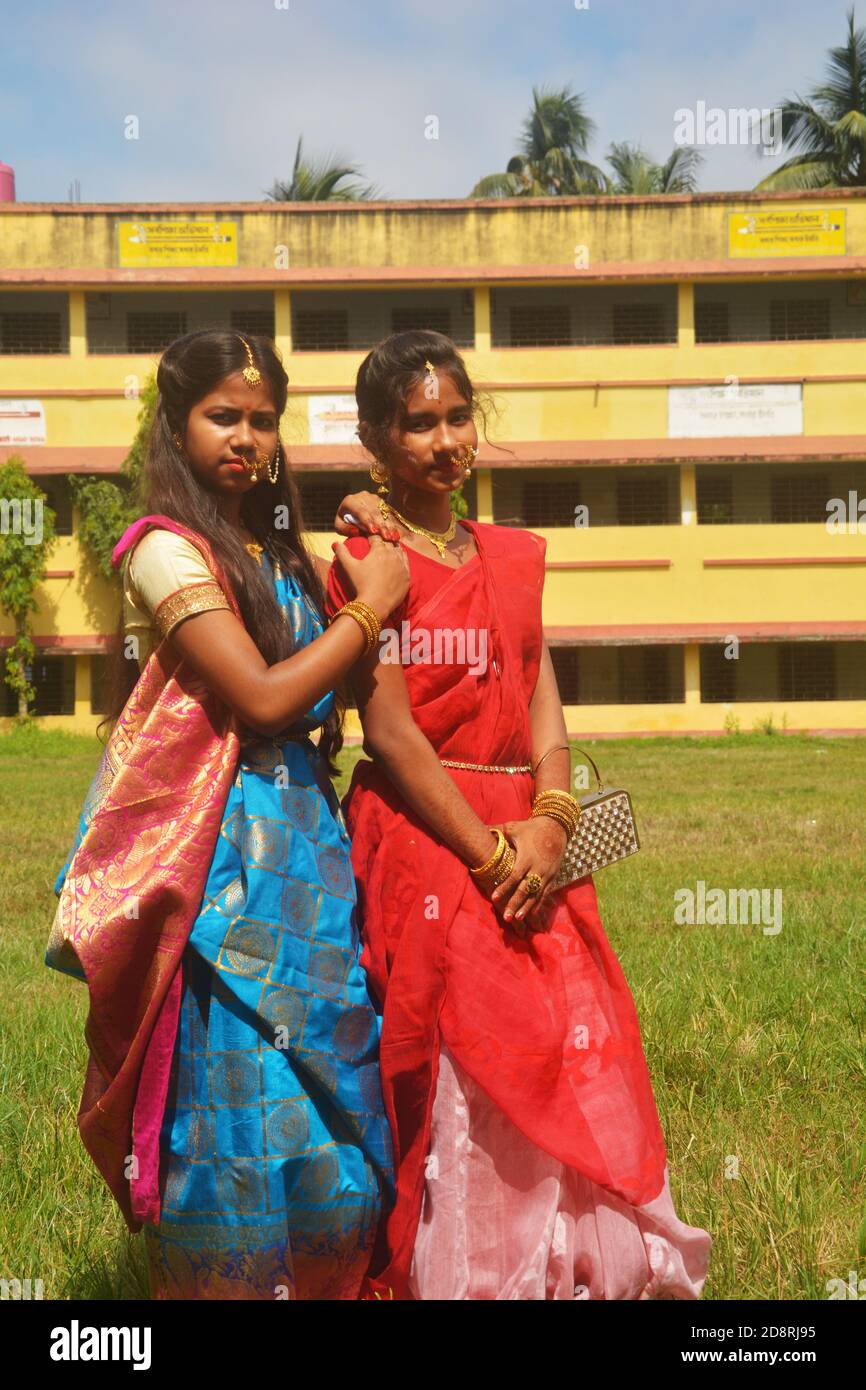 Primo piano di due sorelle che indossano saree tradizionali e gioielli come orecchini a naso, grovigli di tika durante Durga Puja, messa a fuoco selettiva Foto Stock