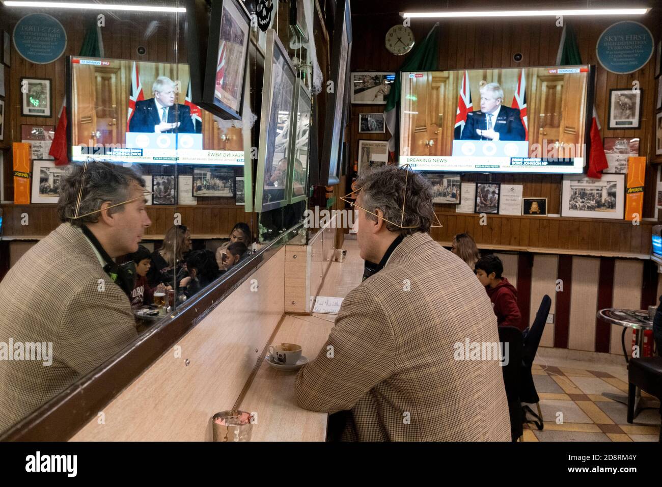 Su uno schermo televisivo di Bar Italia, il famoso caffè italiano di Soho, il primo ministro Boris Johnson si rivolge al Regno Unito in diretta TV per annunciare un secondo blocco nazionale durante la seconda ondata della pandemia di Coronavirus, il 31 ottobre 2020, a Londra, Inghilterra. Le aziende come Bar Italia dovranno chiudere di nuovo, tranne che per le asporto, a partire dalla mezzanotte del giovedì per un periodo di un mese. Foto Stock