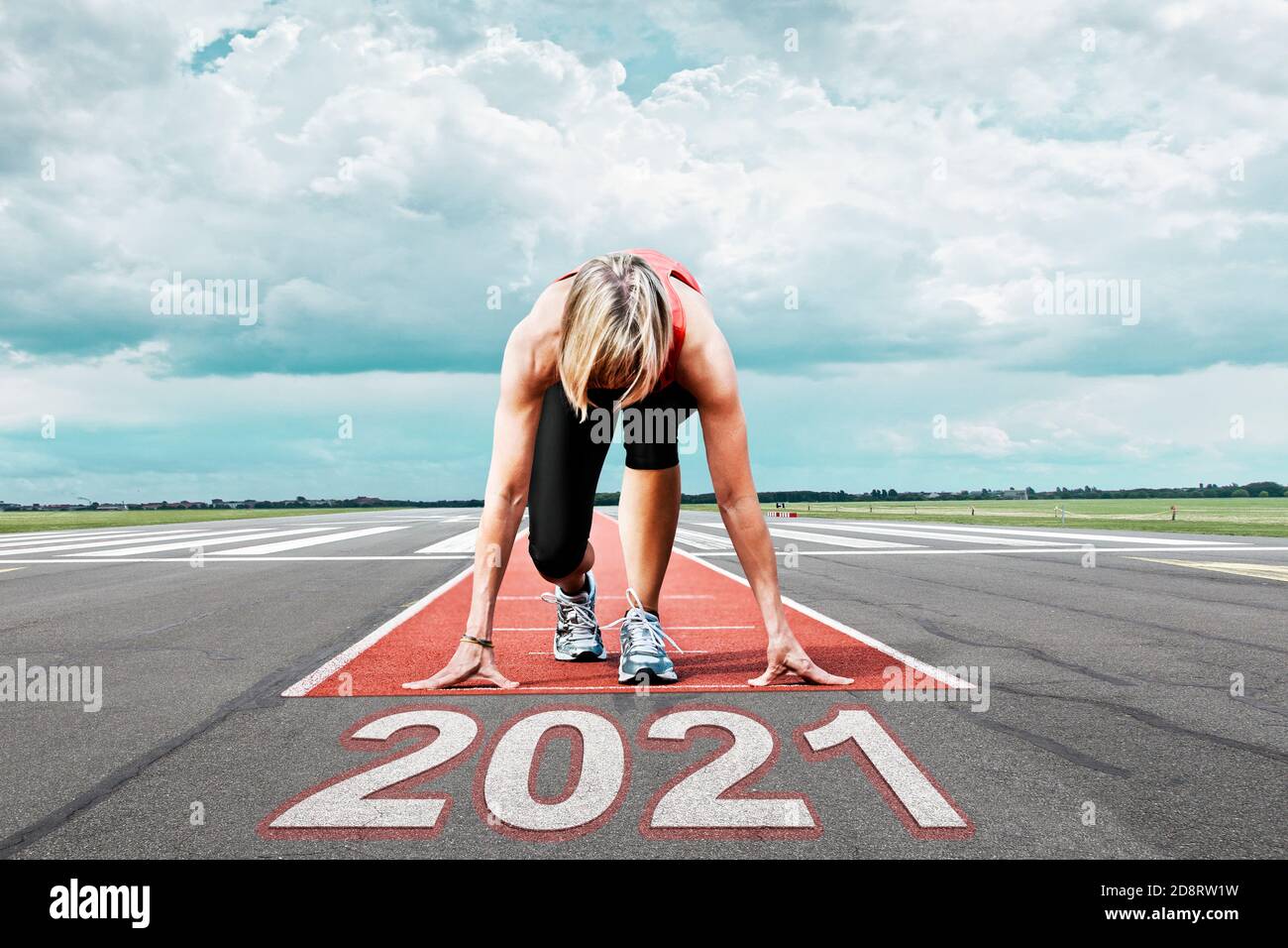 La corridore femminile attende il suo inizio in una pista dell'aeroporto. In primo piano la data dipinta 2021 simboleggia l'anno. Foto Stock
