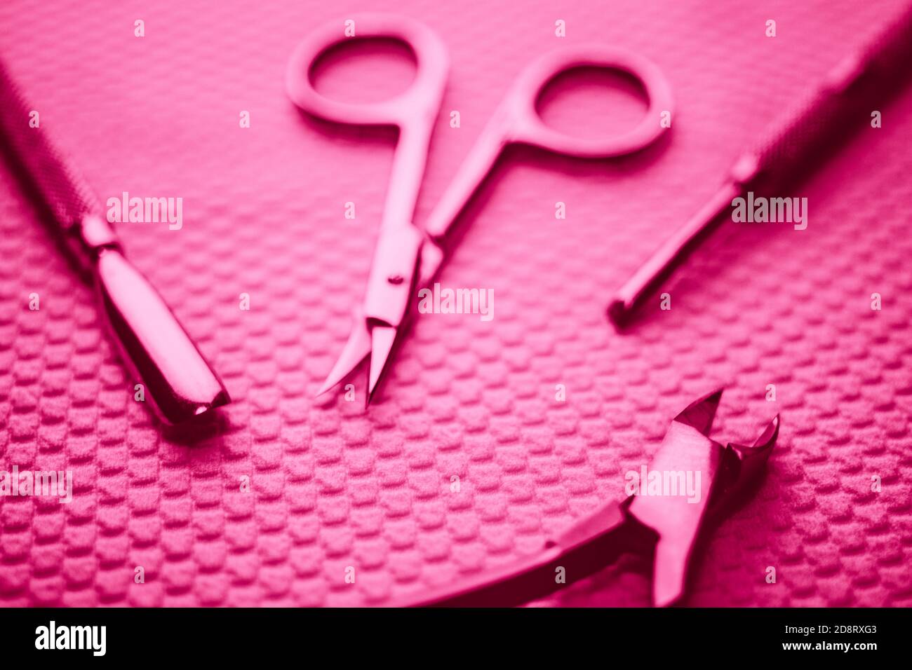 Set di attrezzi per manicure professionali sul tavolo in luce rosa. Foto Stock