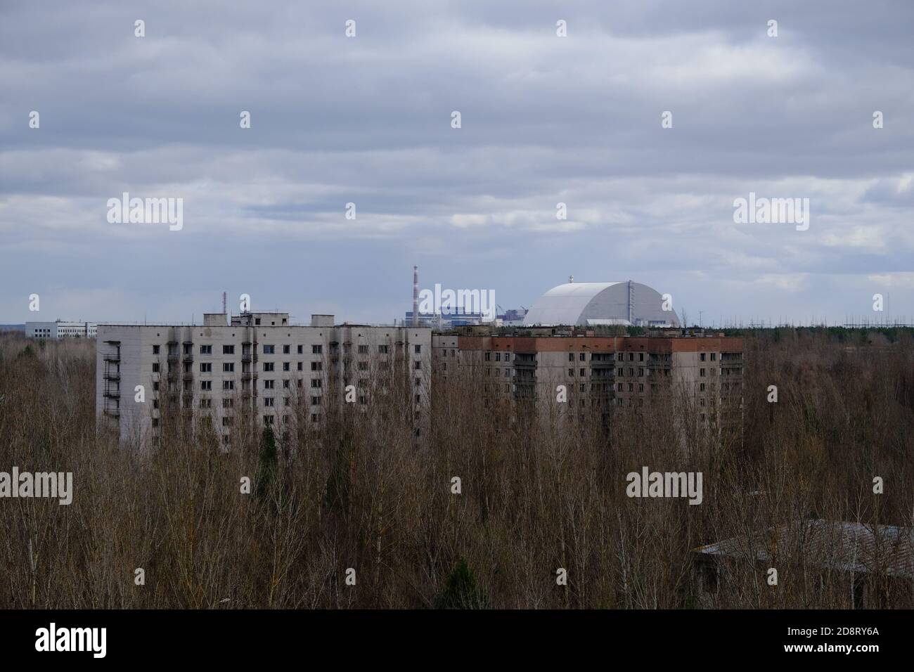 Case abbandonate a Pripyat. Centrale nucleare di Chernobyl e sarcofago protettivo sullo sfondo. Foto Stock