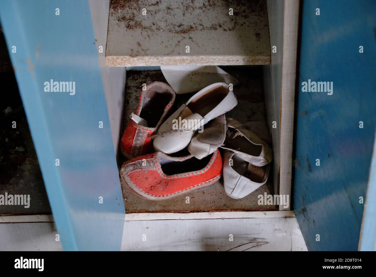 Le piccole pantofole per bambini si trovano sullo scaffale dell'armadio. Scarpe in un asilo abbandonato. Foto Stock