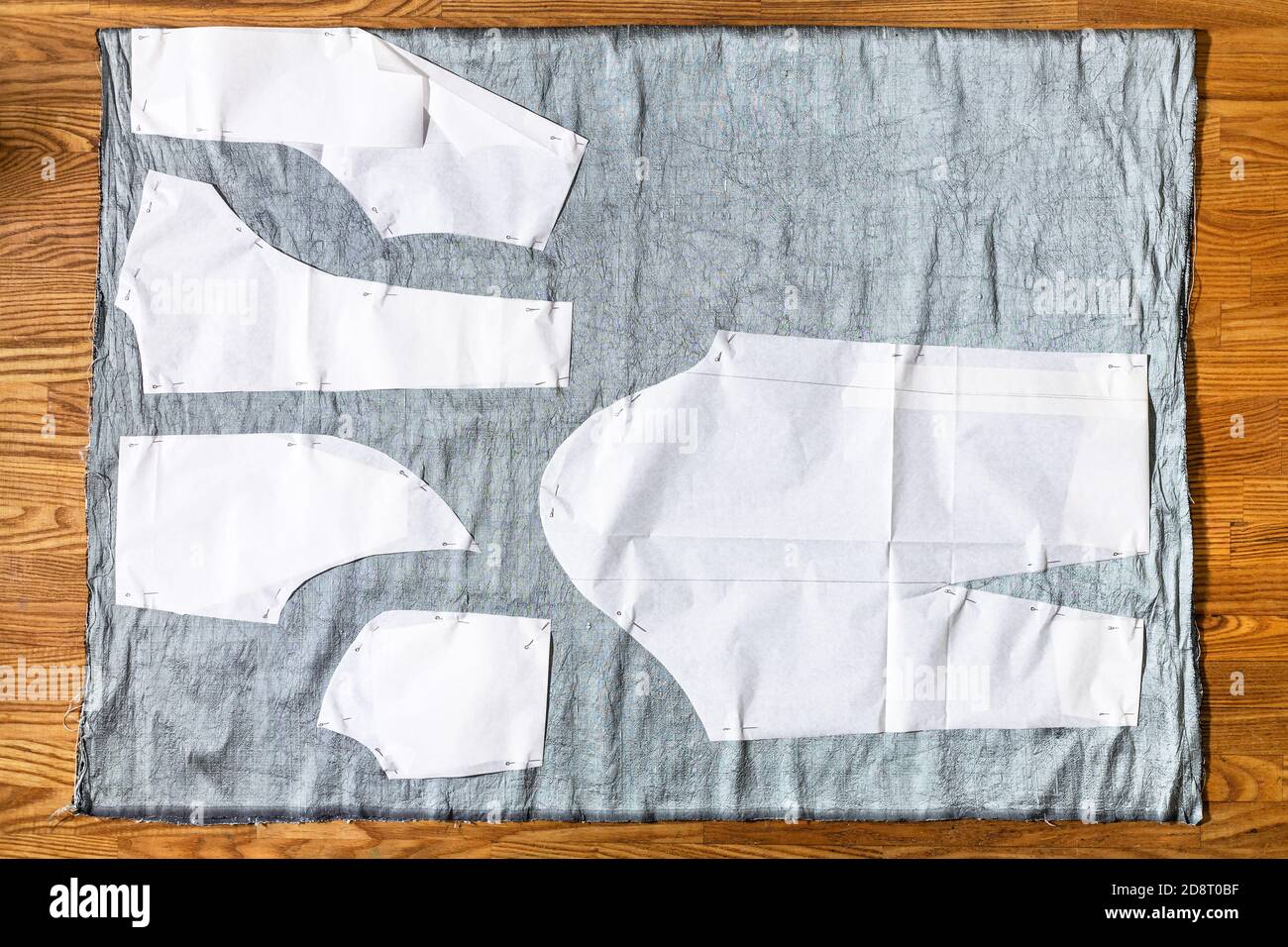 vista dall'alto dei layout del modello di cucitura della carta su tessuto grigio su tavolo di legno a casa Foto Stock