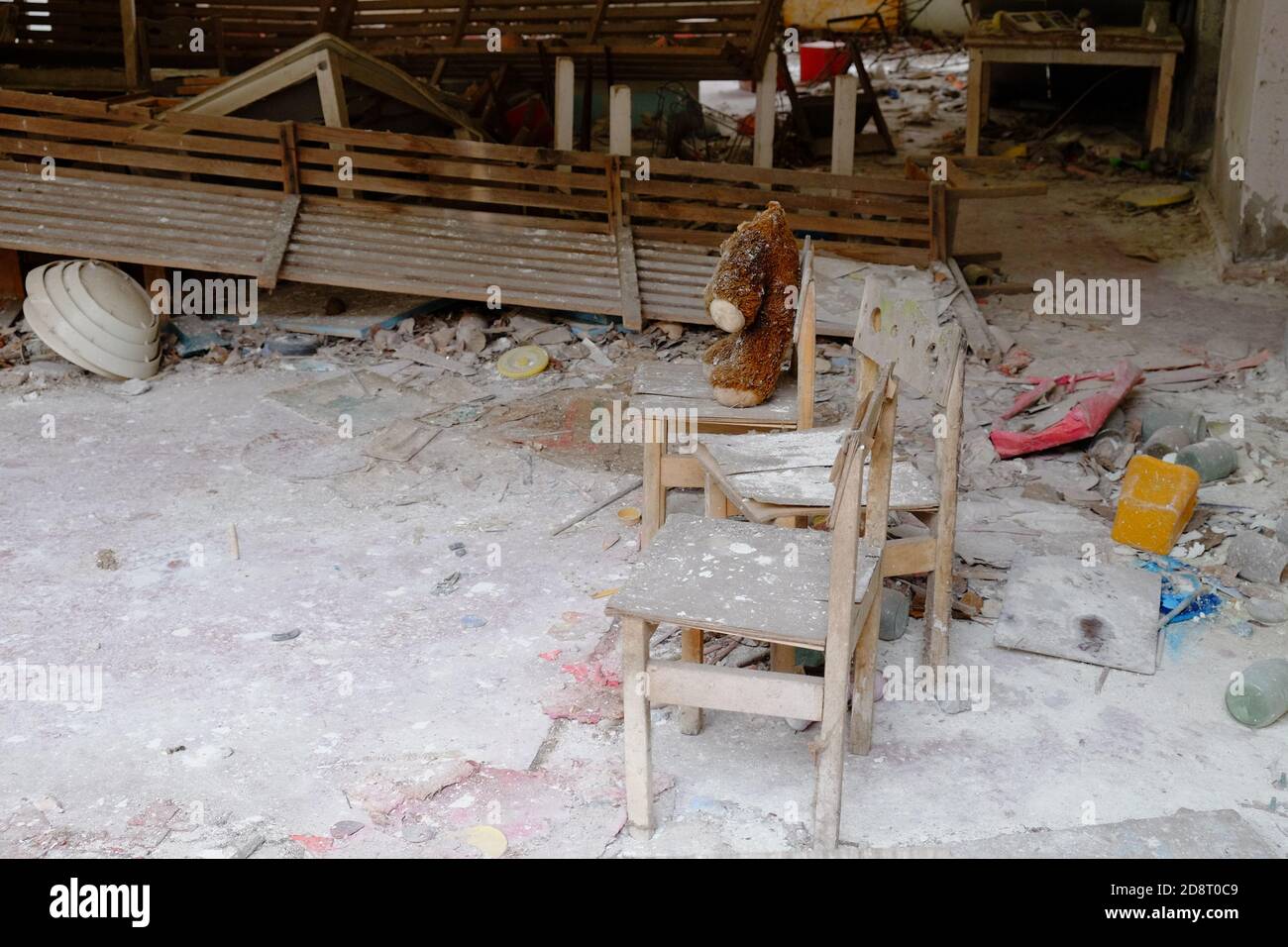 Giocattolo peluche sporco sulla sedia. Un orsacchiotto senza testa in un asilo abbandonato a Pipyat. Foto Stock