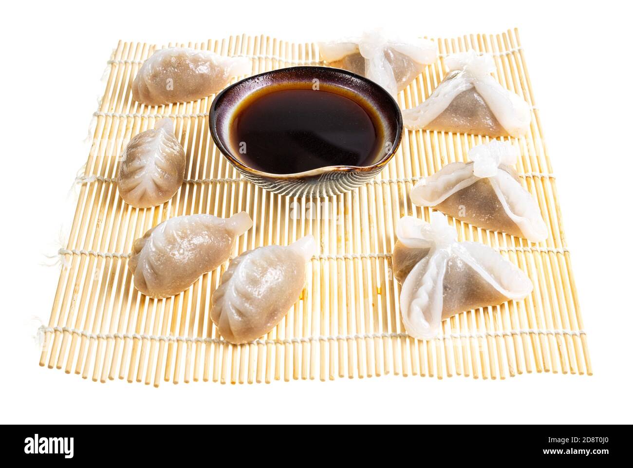 Cucina cinese - vari Dim Sum e salsa di soia in ciotola su tappetino di legno isolata su sfondo bianco Foto Stock