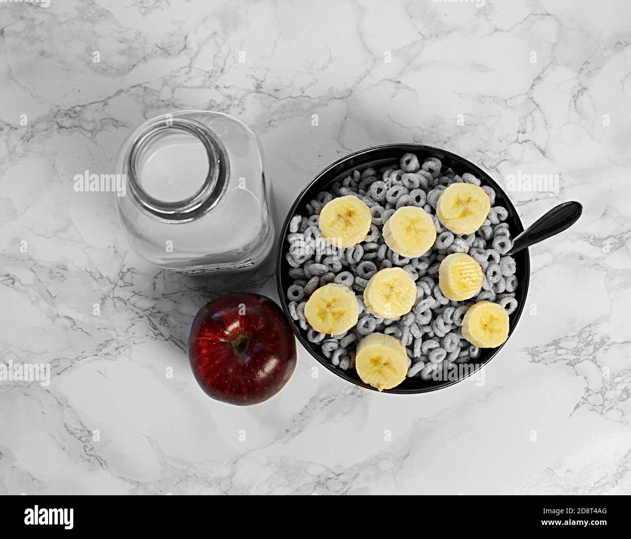 Guardando verso il basso la ciotola di cereali con fette di banana, mela rossa e latte rosa Foto Stock