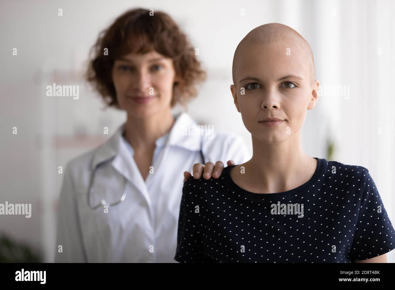 Testa scattata ritratto donna senza capelli in piedi con medico dietro la schiena Foto Stock