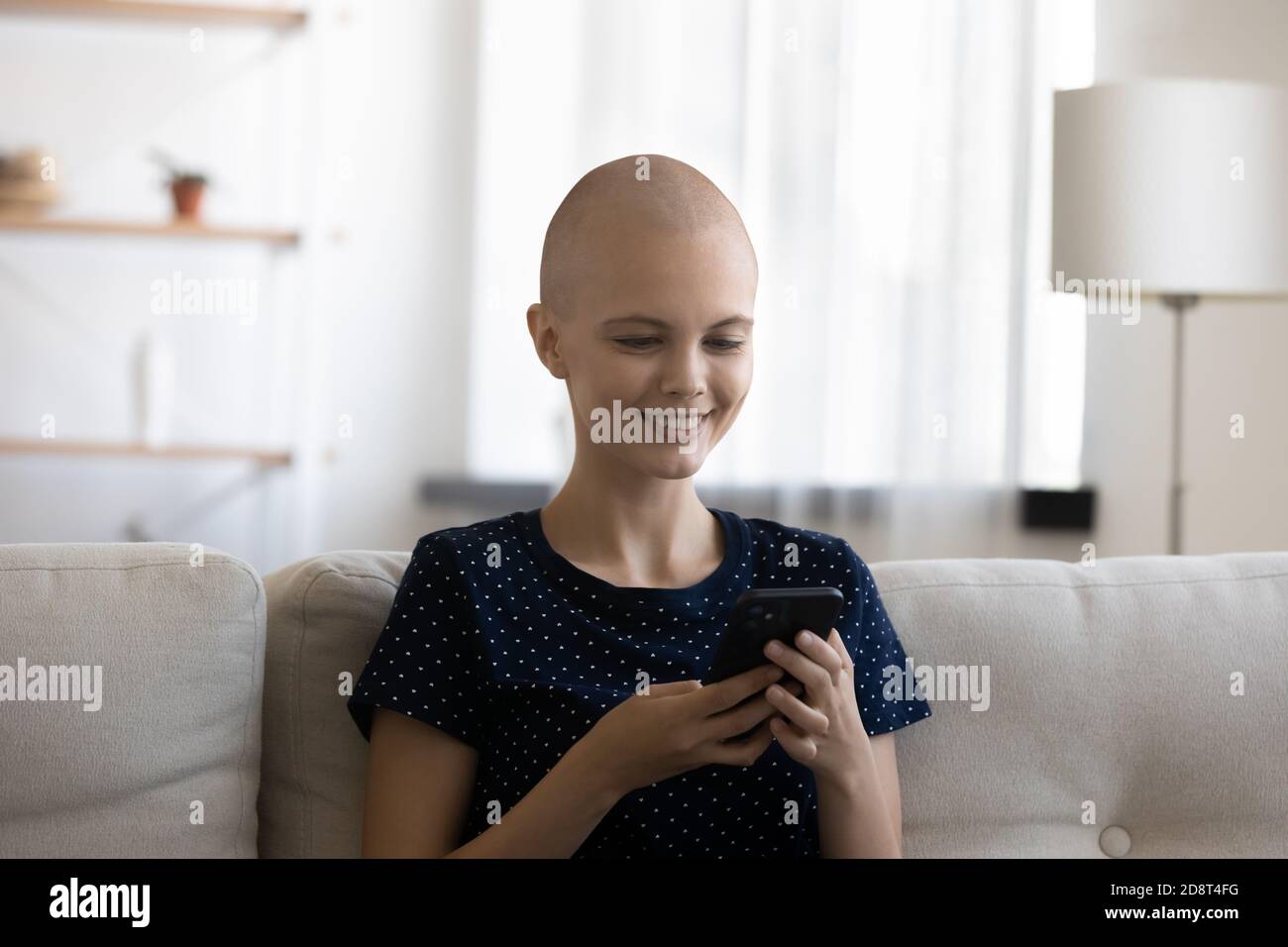Primo piano sorridente donna senza capelli che si diverte con il telefono Foto Stock