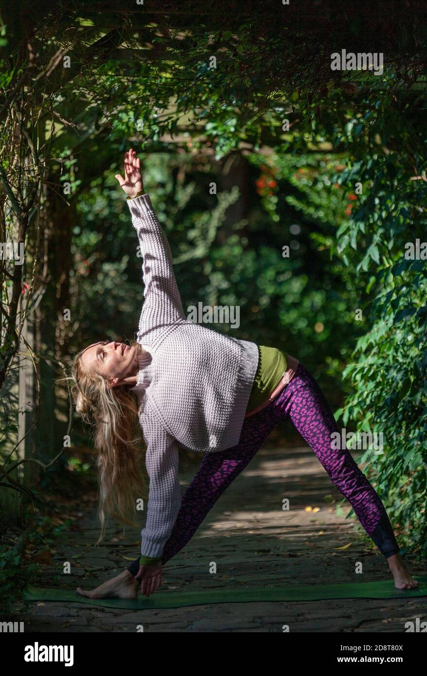 Donna bionda, quaranta anni pratica yoga pone in un ambiente esterno, Londra, Inghilterra Foto Stock