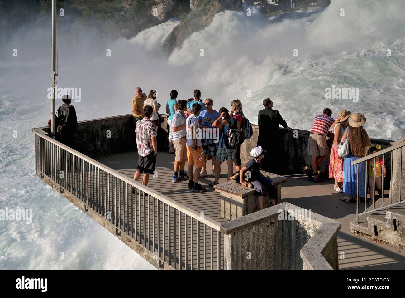 Una piattaforma di osservazione che si snoda dalla riva del fiume sotto lo Schloss Laufen offre ai turisti questa vista mozzafiato e ravvicinata della più grande e potente cascata d'Europa, le cascate del Reno o il Rheinfall, vicino a Schaffhausen, Svizzera settentrionale. L'Alto Reno si diradisce qui su un fiume roccioso a portate medie, in estate, di 600 metri cubi (21,000 piedi cubi) al secondo. Le spettacolari cascate sono una popolare attrazione turistica, attirando decine di migliaia di turisti ogni anno. Foto Stock