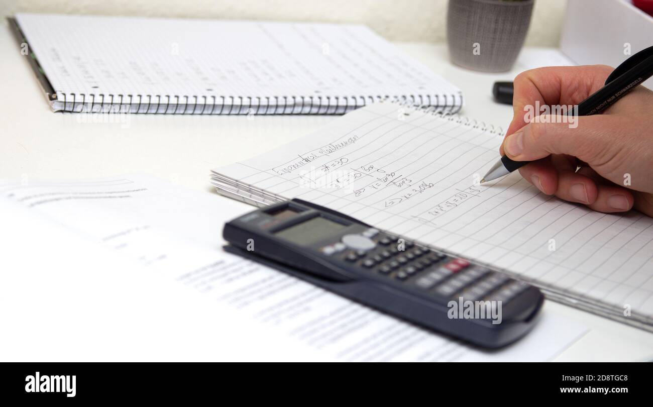 Lo studente risolve le formule matematiche. L'uomo scrive con una penna in un notebook. Compiti. Note in un notebook. Foto Stock