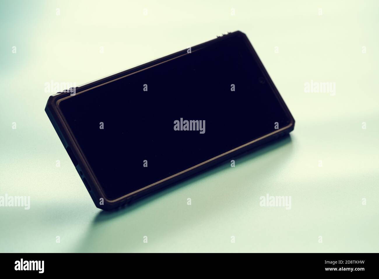 Smartphone con schermo nero e custodia e spazio per la copia colore sfondo blu stile di tonalità e umore Foto Stock