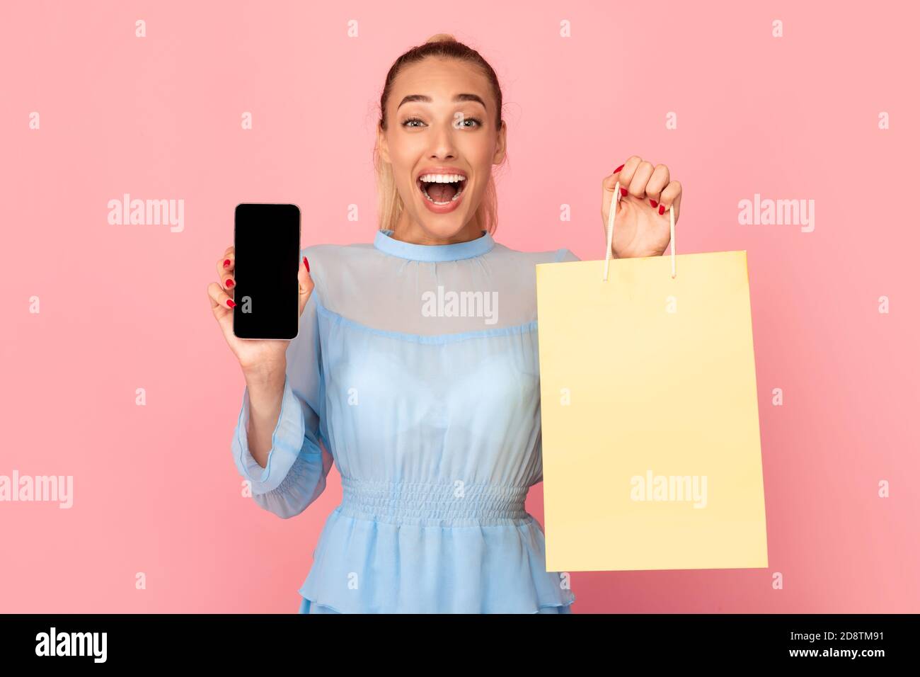 Donna entusiasta che mostra lo schermo nero del telefono e la borsa della spesa Foto Stock