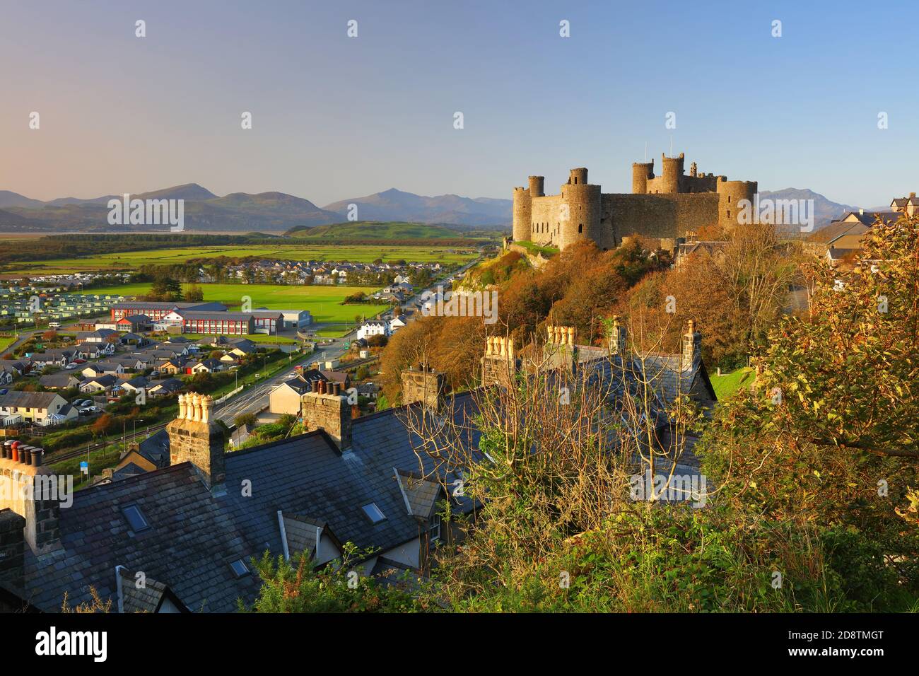 Harlech Castello in tarda serata luce del sole e cielo blu con montagne in lontananza, Snowdonia, Galles del Nord, Regno Unito. Foto Stock