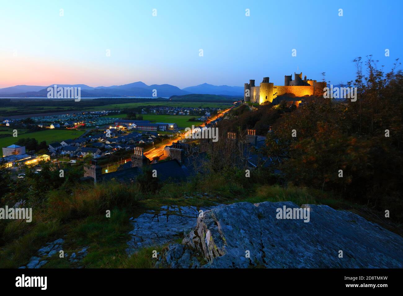 Harlech Castello al crepuscolo con le montagne di Snowdonia in lontananza. Galles, Regno Unito. Foto Stock