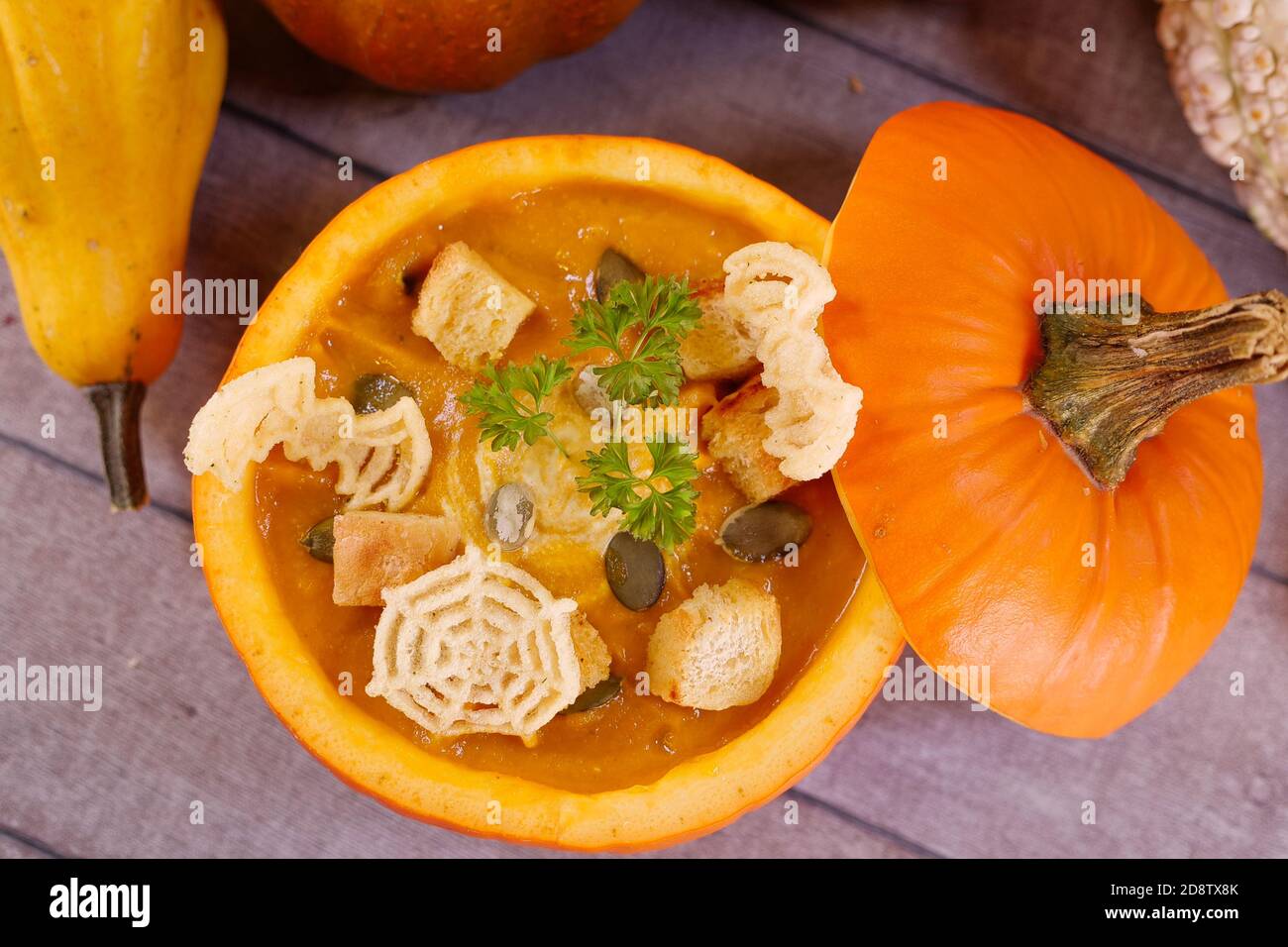 Zuppa di Halloween di zucca. Zuppa vegetariana di carote di zucca in una zucca cava con crema, semi di zucca, prezzemolo e crostini. Autunno, ringraziamento Foto Stock