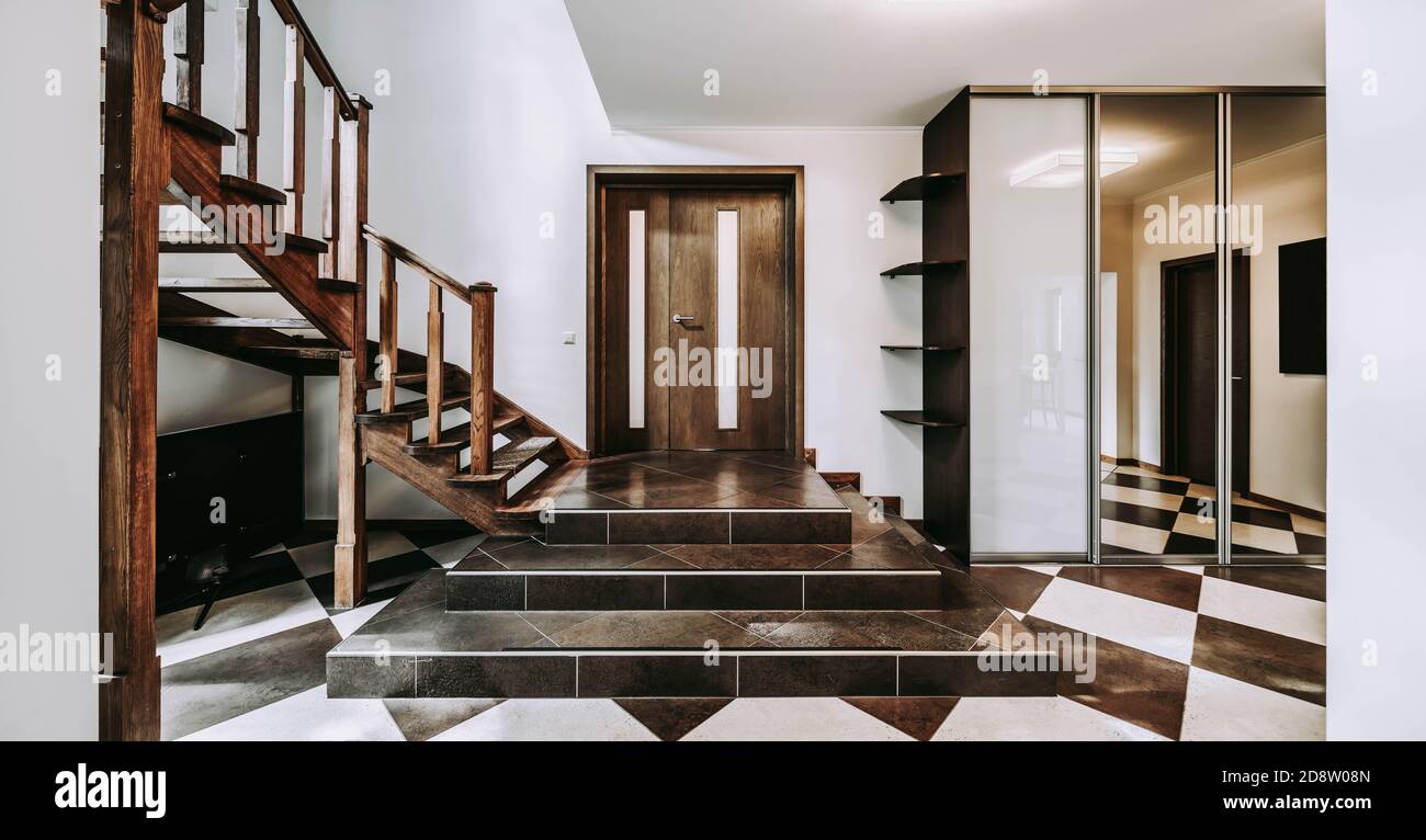 Interno di lusso della hall d'ingresso in appartamento. armadio porta scorrevole a specchio. Scala in legno. Foto Stock