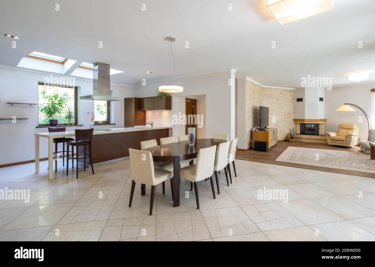 Interni moderni di spaziosi e lussuosi monolocali. Tavolo e sedie in legno. Soggiorno con camino e mobili. Foto Stock