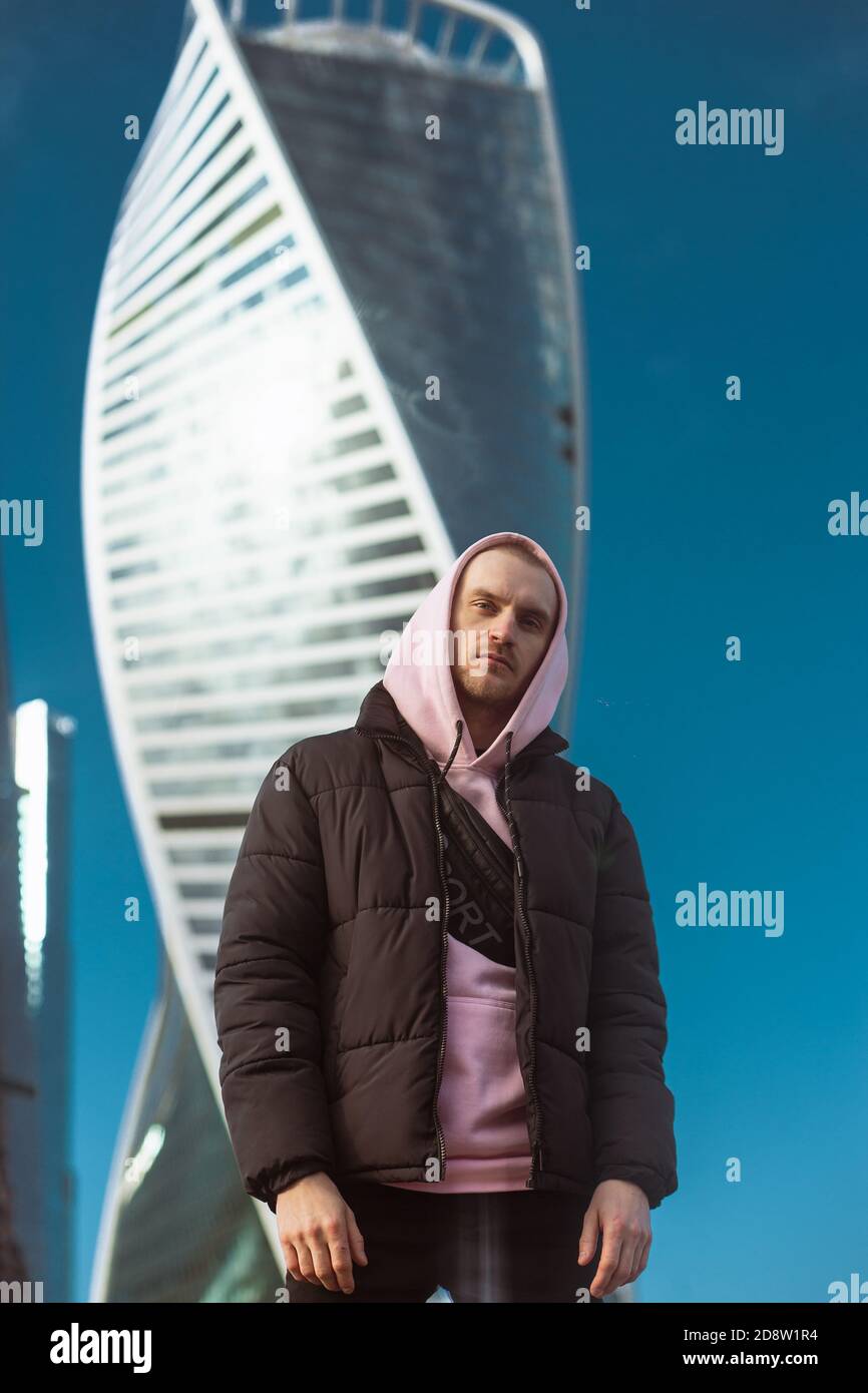 Bell'uomo casual con giacca nera e felpa con cappuccio rosa in piedi su una  vista grattacielo Foto stock - Alamy