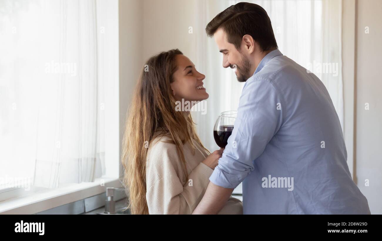 Appassionata coppia amorosa abbracciando in cucina con bicchieri di vino Foto Stock