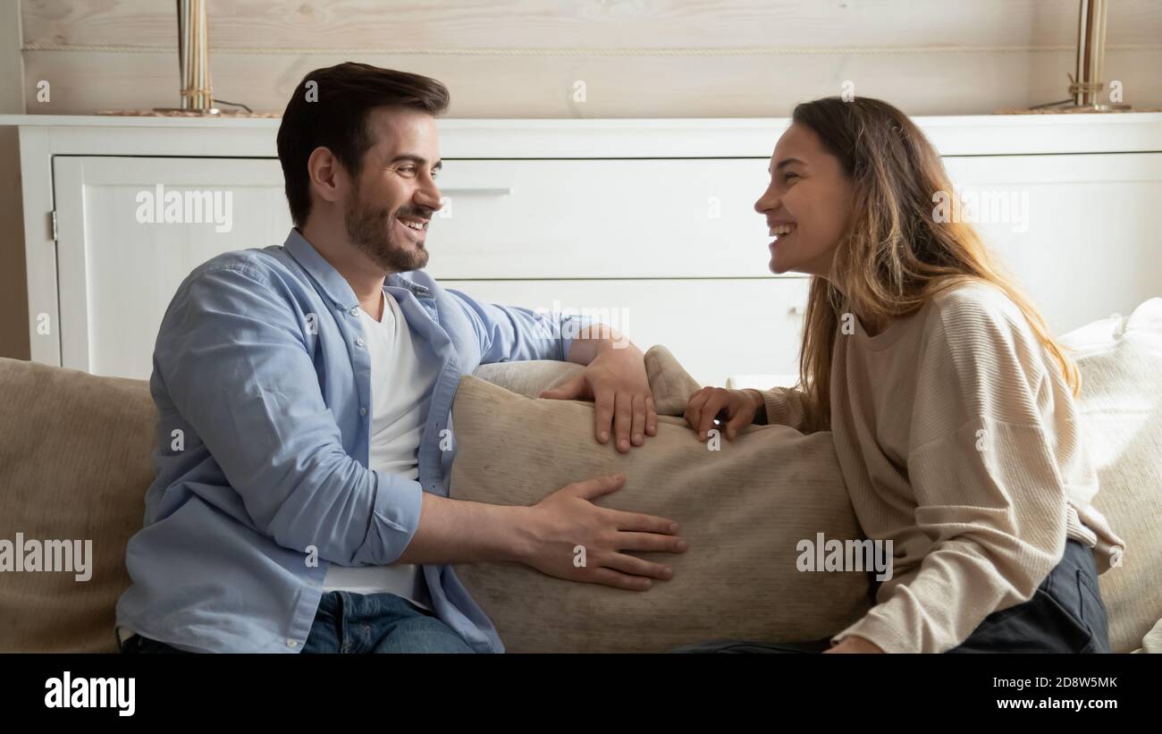 Piacevole coppia millenaria di famiglia che ha conversazione allegra in soggiorno Foto Stock