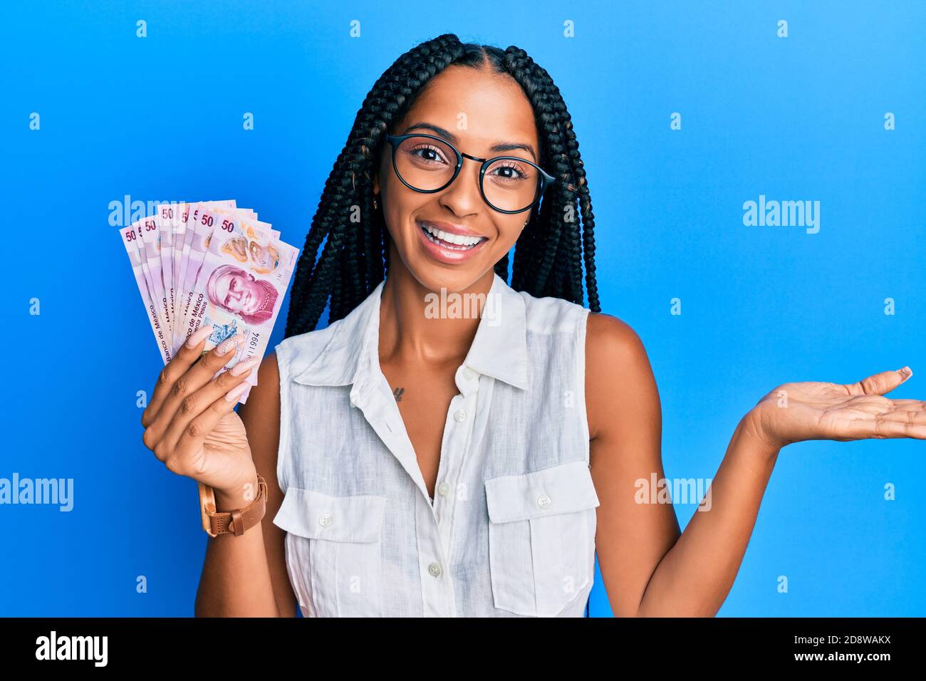 Bella donna ispanica in possesso di 50 pesos messicani banconote celebrare il successo con sorriso felice e espressione vincente con mano sollevata Foto Stock