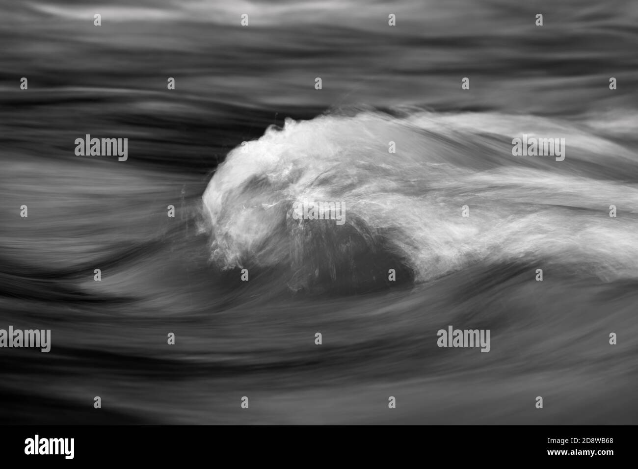 Vista dettagliata dell'acqua fluente di un piccolo fiume, immagine in bianco e nero ad alto contrasto, struttura scorrevole, esposizione prolungata, zona di messa a fuoco stretta Foto Stock