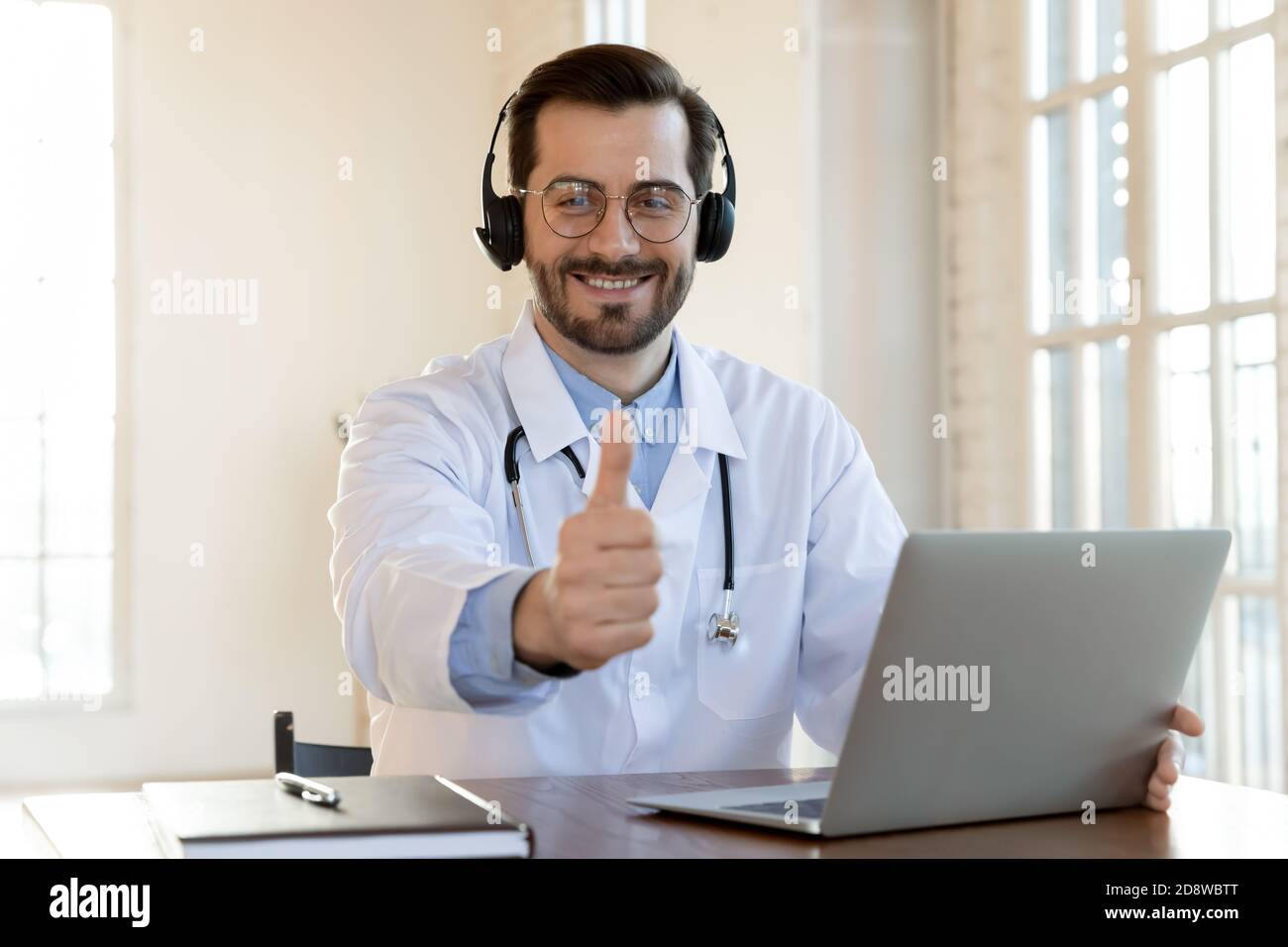 Buon medico in auricolari wireless che consiglia il contatto con la hotline medica Foto Stock