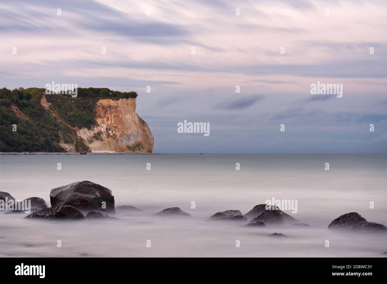 Spiaggia del Mar Baltico, grandi pietre di fronte alla ripida riva di Cape Arkona nella luce della sera, il movimento di acqua e nuvole è stato levigato da lungo tim Foto Stock