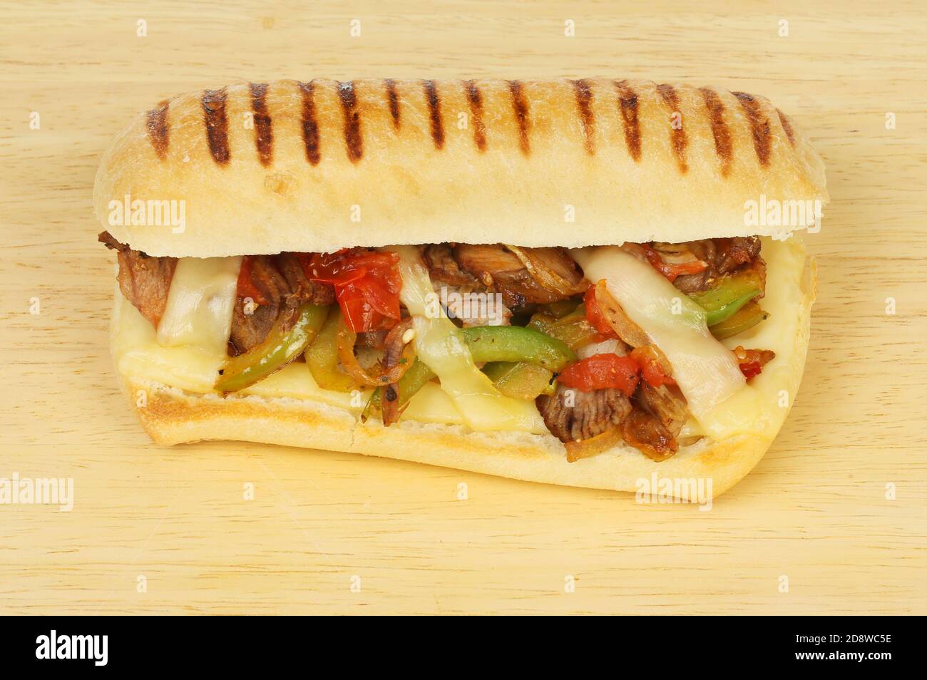 Manzo, cipolla, pepe, pomodoro e formaggio emmental in panini su un tagliere di legno Foto Stock