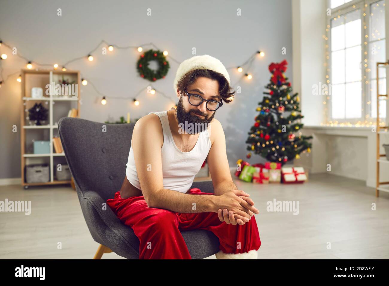 Positivo divertente Santa uomo in casa costume festivo seduta dentro poltrona Foto Stock