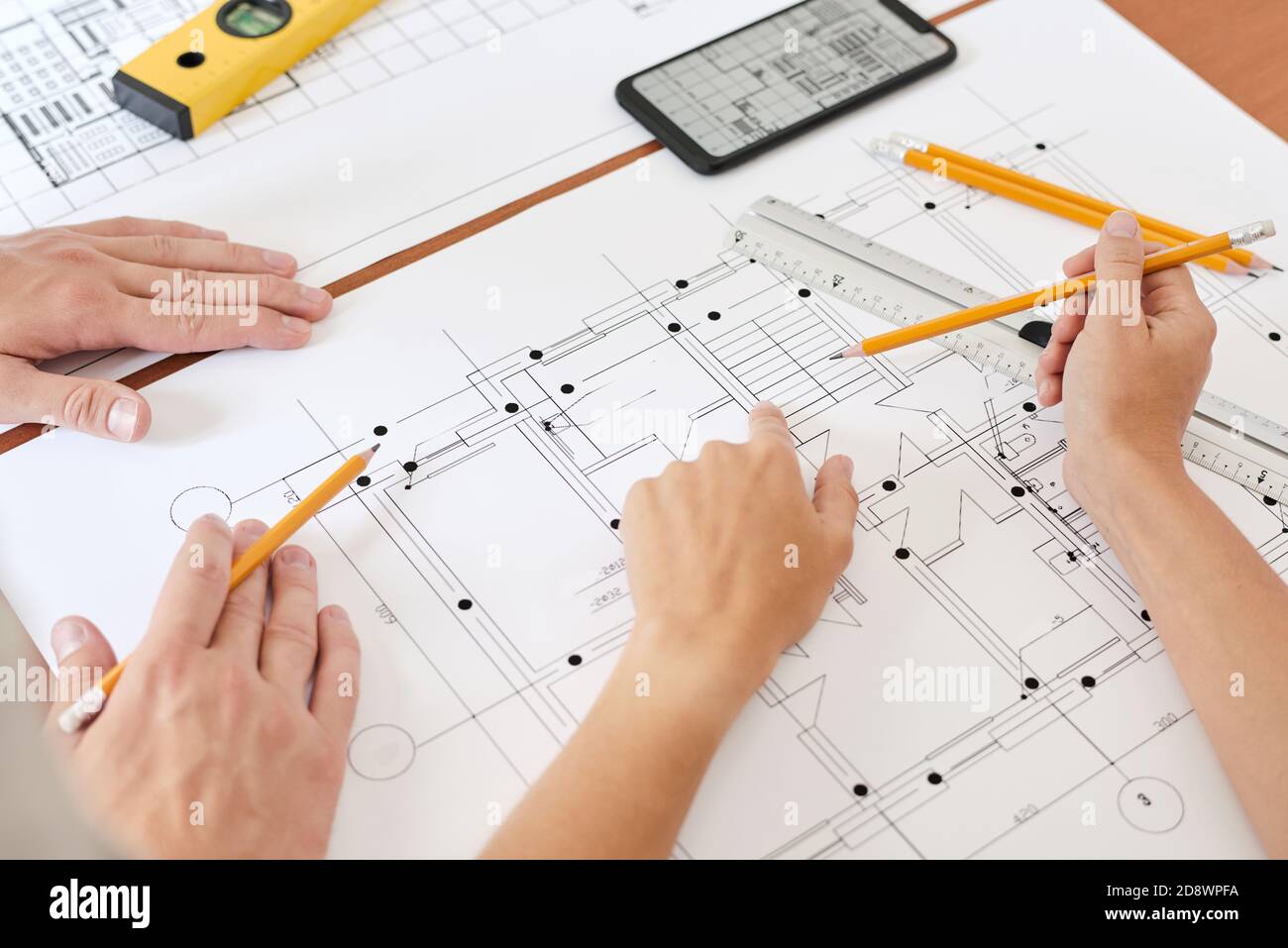 Mano di giovane ingegnere femminile con matita che punta al disegno di nuovo edificio Foto Stock