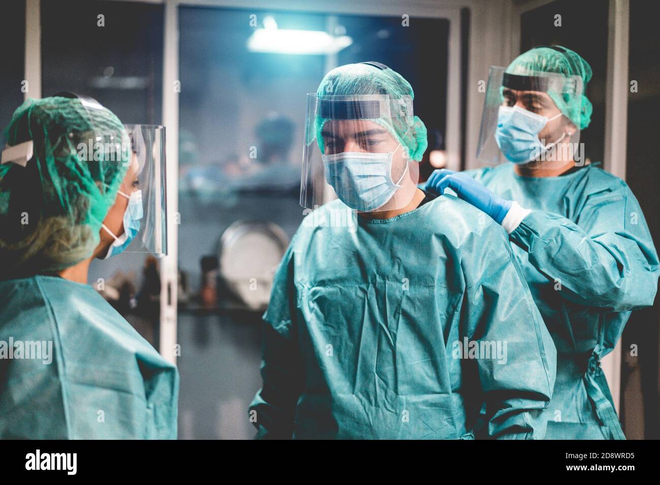 Medici e infermieri si preparano a lavorare in ospedale per l'intervento chirurgico durante l'epidemia di coronavirus pandemic - operatori medici che si vestono all'interno c Foto Stock