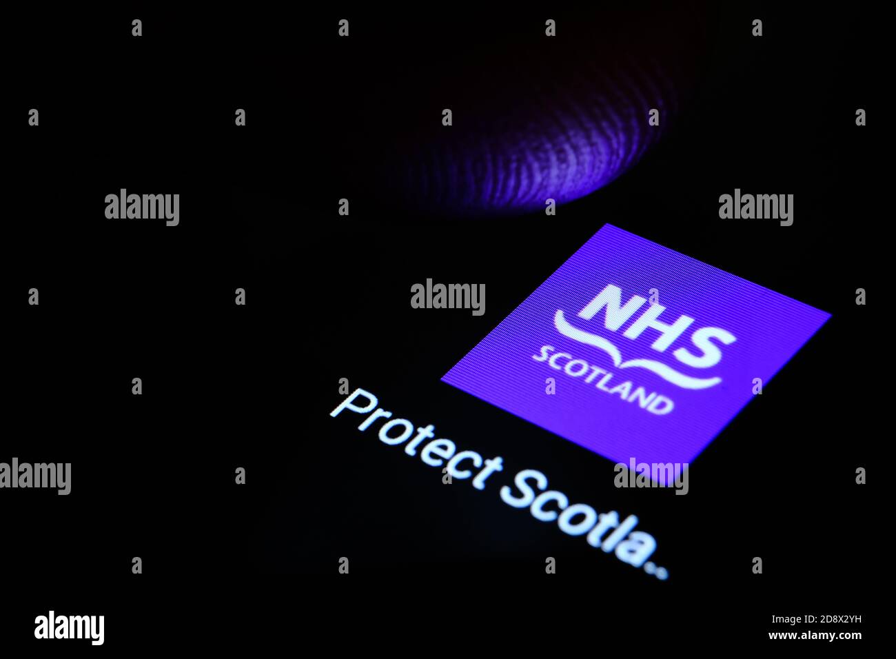 App NHS SCOTLAND visualizzata sullo schermo scuro dello smartphone e un dito sfocato sopra di essa. Applicazione di tracciamento del contatto. Foto Stock