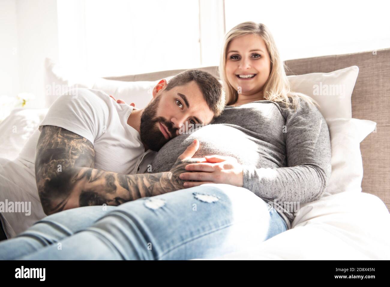 l'uomo si addossò al piccolo grumo di sua moglie incinta, che si trova sul letto Foto Stock